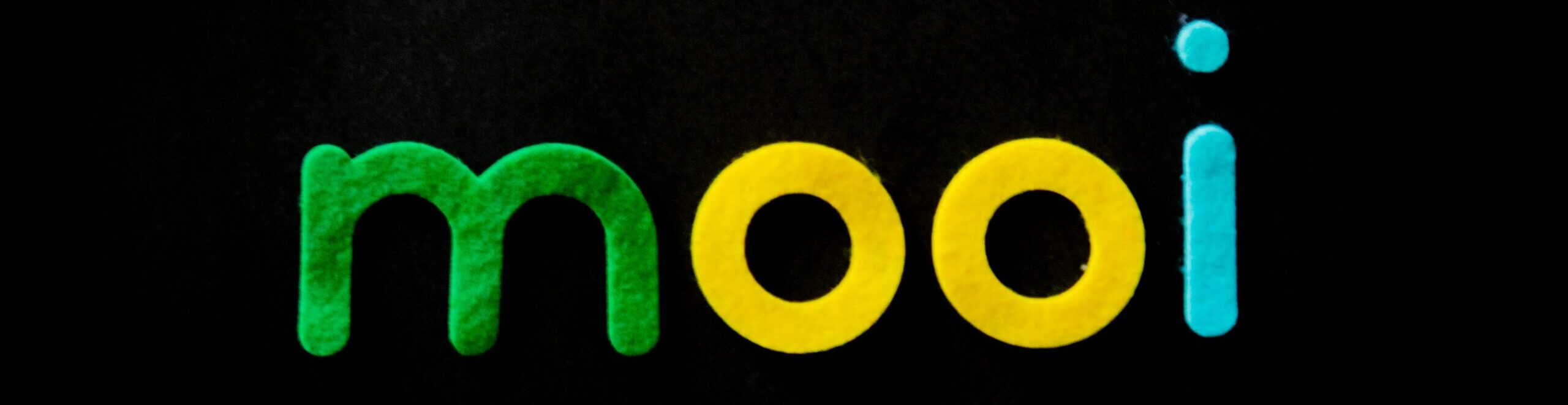 Vibrant and modern typography spells 'mooi' in green, yellow, and blue on black.